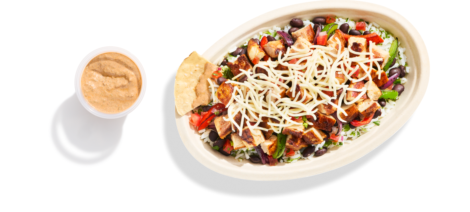A Chipotle Chicken Burrito Bowl with White Rice, Black Beans, Shredded Cheese, Fajita Peppers, Fresh Tomato Salsa, and a freshly made tortilla chip dipped in a side of our new Adobo Ranch.